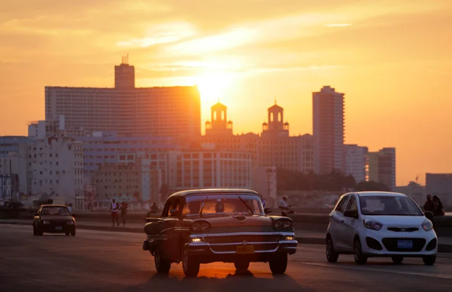 Classic American cars on Malecón seawall at sunset